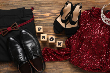 Wall Mural - Male pants with female dress, shoes and text PROM on wooden background