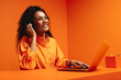 © Jacob Lund - Smiling woman customer support agent in vibrant orange monochromatic office setting