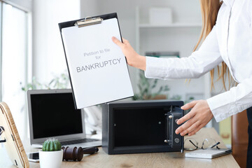 Wall Mural - Businesswoman with empty safe and petition to file for bankruptcy in office, closeup