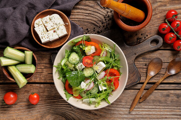 Wall Mural - Bowl of fresh vegetable salad with cucumber and feta cheese on wooden background