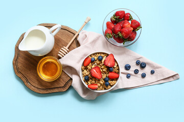 Wall Mural - Napkin, bowl with tasty granola and berries on blue background