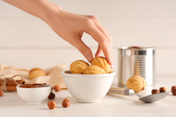 Canvas Print - Woman taking tasty walnut shaped cookies with boiled condensed milk on white wooden table