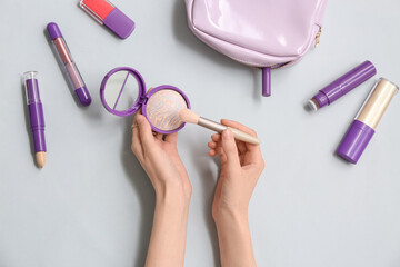 Wall Mural - Female hands with makeup powder, brush and different cosmetics on grey background