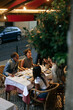 © bernardbodo - Friends enjoying dinner together at outdoor restaurant