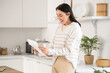 © Pixel-Shot - Happy young woman with refund form in kitchen