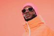 © Papukos - Stylish model posing in orange jacket and pink beanie