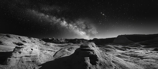 starry black and white landscape featuring diverse textures with rocky formations in foreground unde