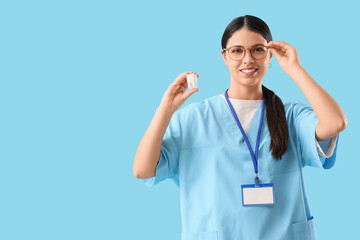 Poster - Female dentist with tooth model on blue background