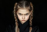 A serious young girl with braided hair wearing a black outfit against a dark background.
