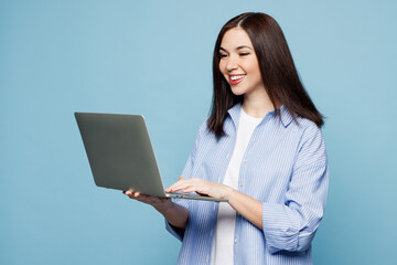 Sticker - Young fun Caucasian IT woman she wears shirt casual clothes hold use work on laptop pc computer chatting online isolated on plain pastel light blue cyan background studio portrait. Lifestyle concept.