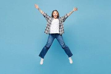 Canvas Print - Full body young shocked surprised woman wears checkered grey shirt casual clothes jump high with outstretched hands legs isolated on plain pastel light blue cyan background studio. Lifestyle concept.