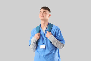 Poster - Male medical intern with backpack on light background