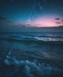 © SecretCanvas - Peaceful nighttime ocean photo with a wave crashing on the beach beneath a starry sky and nebula in the distance ocean wallpaper inspiration