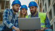© Ali Hamza Tullah - Focused man and woman discussing apartment renovation plan or construction work with builder, Construction worker in blue helmet and reflective vest showing something on laptop to young family couple.