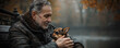 © PetalFlower - A senior man gently cradles a small, adorable puppy on a park bench.  Autumnal colors blur in the background, creating a serene and heartwarming scene.
