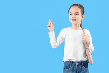 Wall Mural - Cute girl with bag pointing at something on blue background