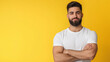 © Maksym - A confident bearded man in a casual t-shirt poses with arms crossed, his happy expression glowing against a warm background. The portrait embodies self-assurance and positivity.