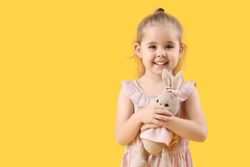 Canvas Print - Cute little girl with toy bunny on yellow background