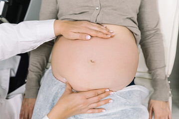 Gynecologist examining pregnant woman's belly in medical clinic