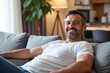 © SimpleDesignStudio - Smiling Middle-Aged Caucasian Man Relaxing on Couch in Modern Living Room with Stylish Decor, Radiating Comfort and Joy at Home