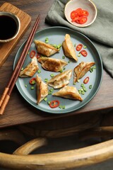 Canvas Print - Delicious fried gyoza dumplings with green onions and chili peppers served on wooden table, flat lay