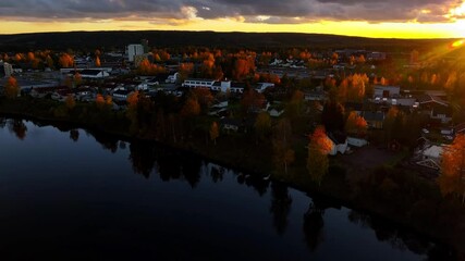 Wall Mural - Breathtaking sunset with golden sun rays spreading on riverside houses and trees