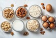 © ANUAR - Assorted Healthy Food Ingredients for Baking and Cooking in Bowls Including Nuts, Oats, Milk, and Eggs on a Light Surface