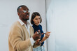 © qunica.com - Two colleagues engage in a dynamic brainstorming session, exchanging and discussing ideas on a whiteboard in a contemporary office setting, highlighting collaboration and creative problem-solving.