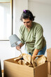 © ADDICTIVE STOCK - Trans woman unpacking in new home, embracing fresh beginnings