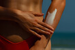 © Mirrorstudio - Woman applying sunscreen on arm at beach under bright sunlight. Skin care, sun protection