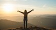 © rdkcho - Woman standing on mountain top with arms outstretched at sunset