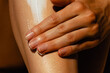 © Mirrorstudio - Close-up of adult female applying moisturizer on leg. Skin care, sun protection