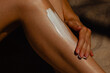 © Mirrorstudio - Female applying sunscreen on leg for summer skincare protection. Skin care, sun protection