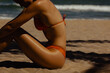 © Mirrorstudio - Silhouette of young hispanic female in orange bikini relaxing on sunny beach. Skin care, sun protection