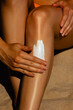 © Mirrorstudio - Female applying sunscreen on legs at beach for skin protection. Skin care, sun protection