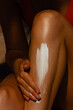© Mirrorstudio - Sun protection application on female leg with sunscreen cream in warm light. Skin care, sun protection