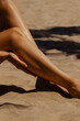 © Mirrorstudio - Sun-kissed female legs on sandy beach. Skin care, sun protection