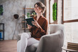 © deagreez - Photo of attractive young woman sit armchair read book wear brown satin shirt modern office room interior indoors workspace