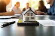 © Gibster - Insurance and Security, Protection, Safety. Miniature house model on a table with people discussing in the background.