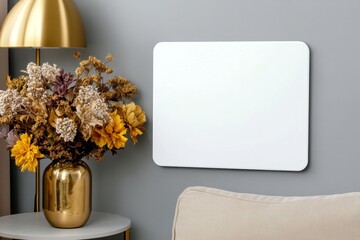Poster - A photo of a large white picture frame mockup on the wall in an elegant and cozy living room, with a sofa featuring beige cushions, a gold floor lamp, a round coffee table with vases full of