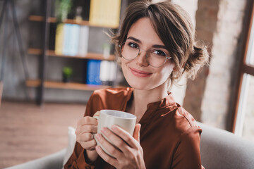 Wall Mural - Photo of pretty young girl drinking tea charming smile wear brown silk shirt coworking successful nice light office