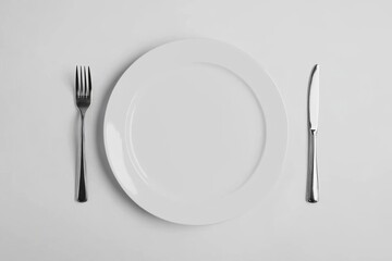 Canvas Print - White plate with fork and knife isolated on a white background, top view, flat lay. A simple, clean, minimalistic background concept of dinnertime or food service. Copy space available. High-quality,