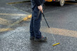 © Tosh Lubek - Gas Engineer Wearing PPE Using Long Handle Combustible Gas Leak Detector With Yellow Probe at Ground Level in City Street
