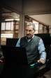 © Marko - Senior man working at desk with laptop in office environment
