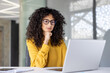 © Liubomir - Businesswoman serious and thinking working inside office with laptop. Woman focused and concentrated typing on keyboard, preparing online presentation, investment report.