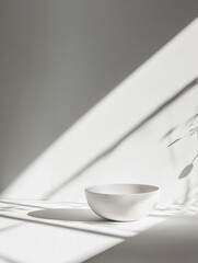 Leinwandbilder - White bowl on surface illuminated by soft sunlight with shadow patterns creating a serene atmosphere. Generative AI