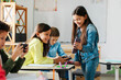© Home-stock - Break at school. Schoolgirl showing cellphone to friends, sitting in classroom, capturing the modern and interactive side of education