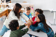 © Home-stock - Team of diverse school children joining hands, sitting in circle in classroom, having bonding moment, feeling united and supported