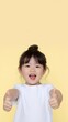 © AlazySM - Adorable 2-Year-Old Girl Giving Double Thumbs-Up with a Big Smile on a Yellow Background
