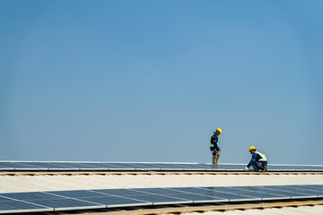 Wall Mural - two engineers install solar panels on a rooftop, wearing safety gear and helmets. the scene showcase